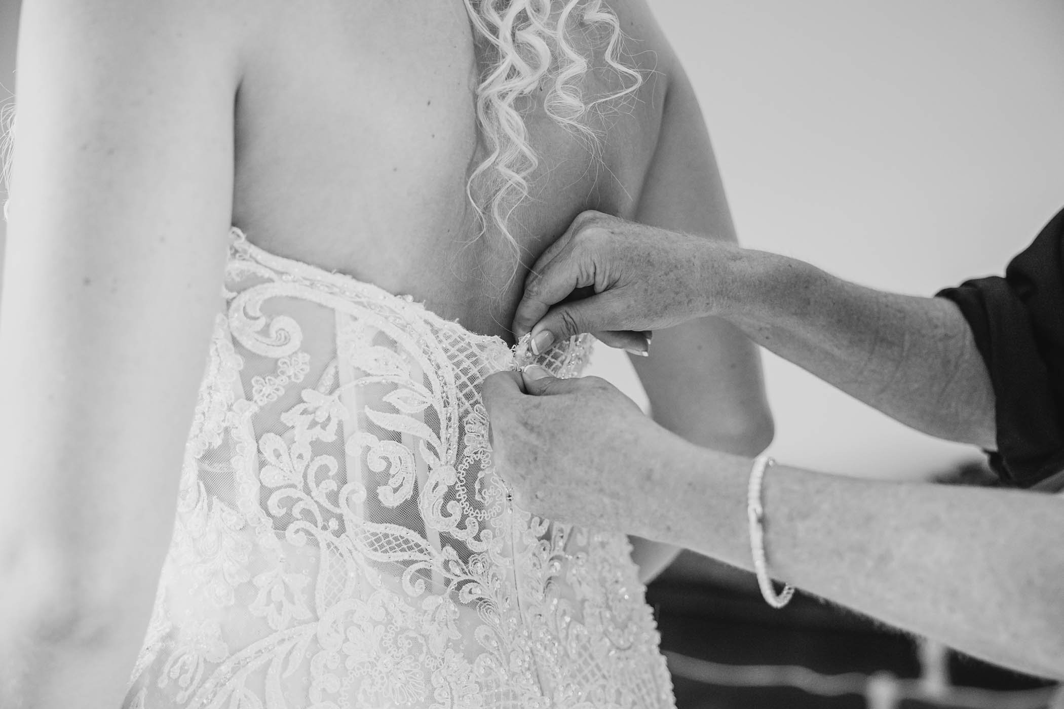 Mother helps bride into wedding dress