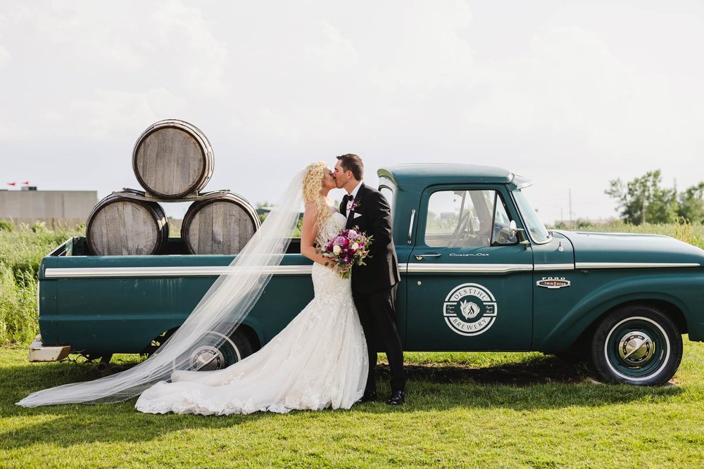 Bride and groom kiss with Destihl Brewery truck