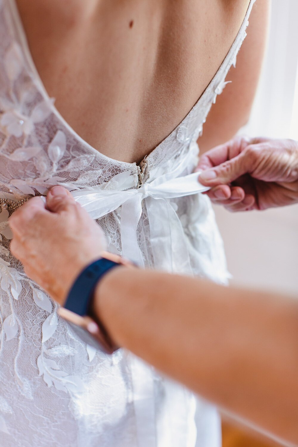 Mother tying bow on wedding dress