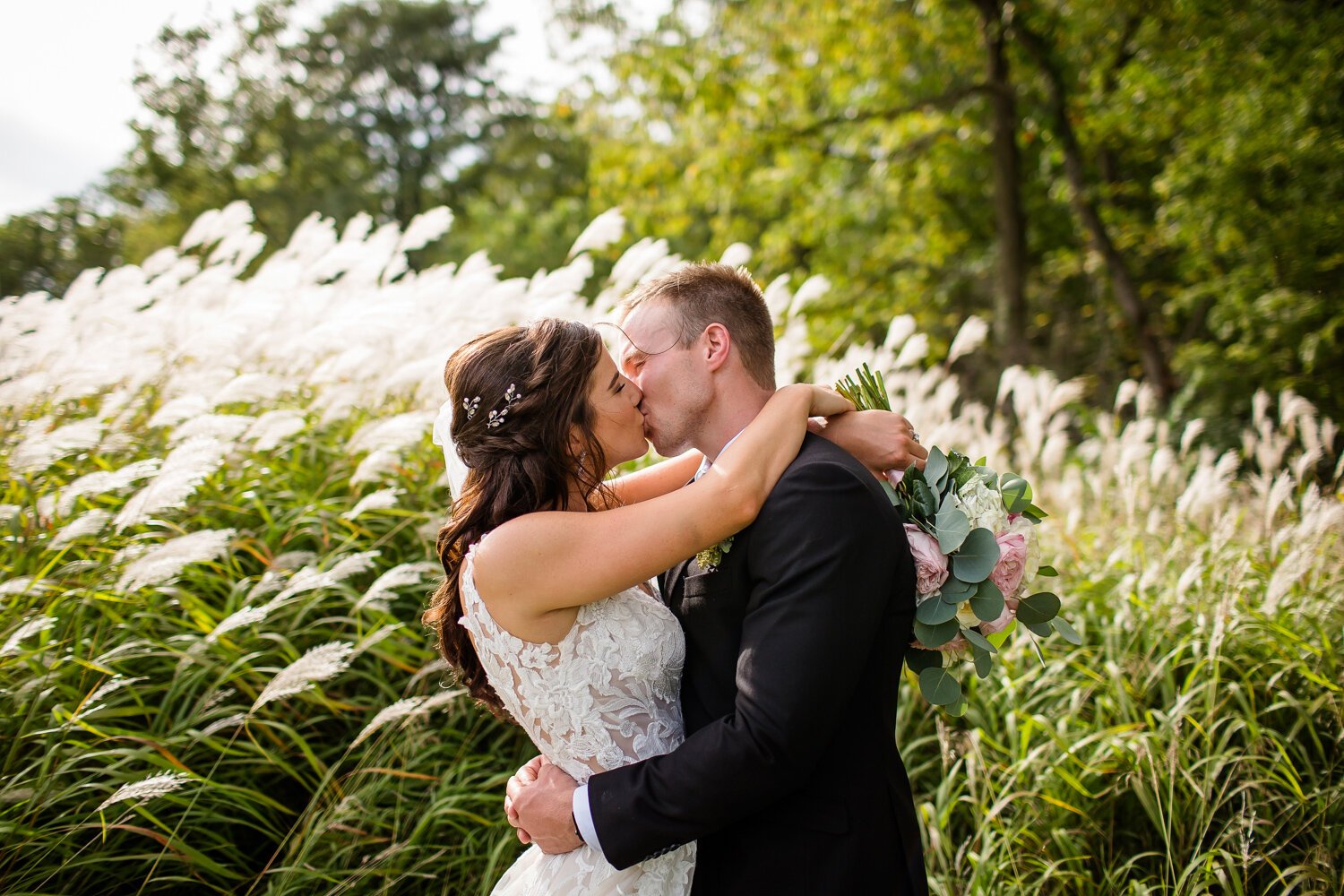 Bride and groom kiss with tall grass