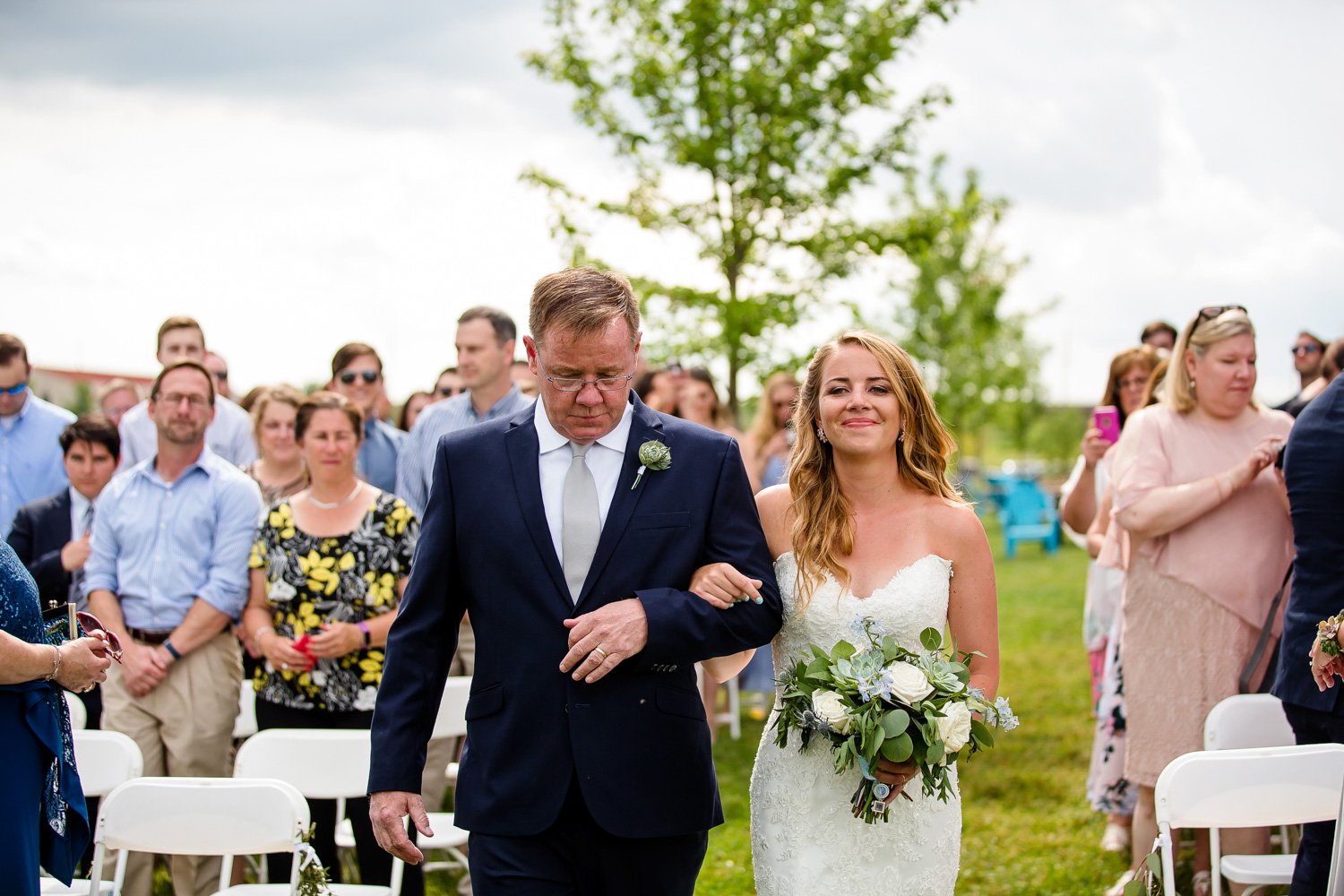 Father walks bride down aisle at outdoor wedding ceremony