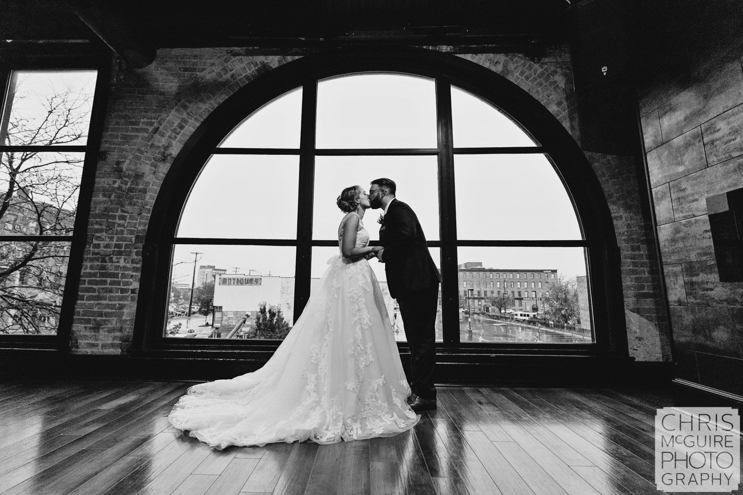 bride groom kissing in front of window