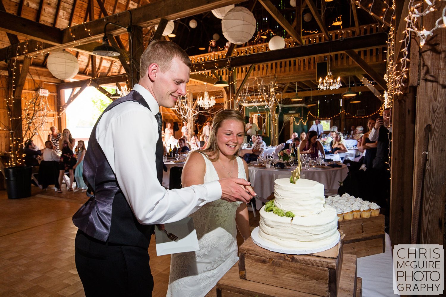 bride groom cut cake in barn wedding