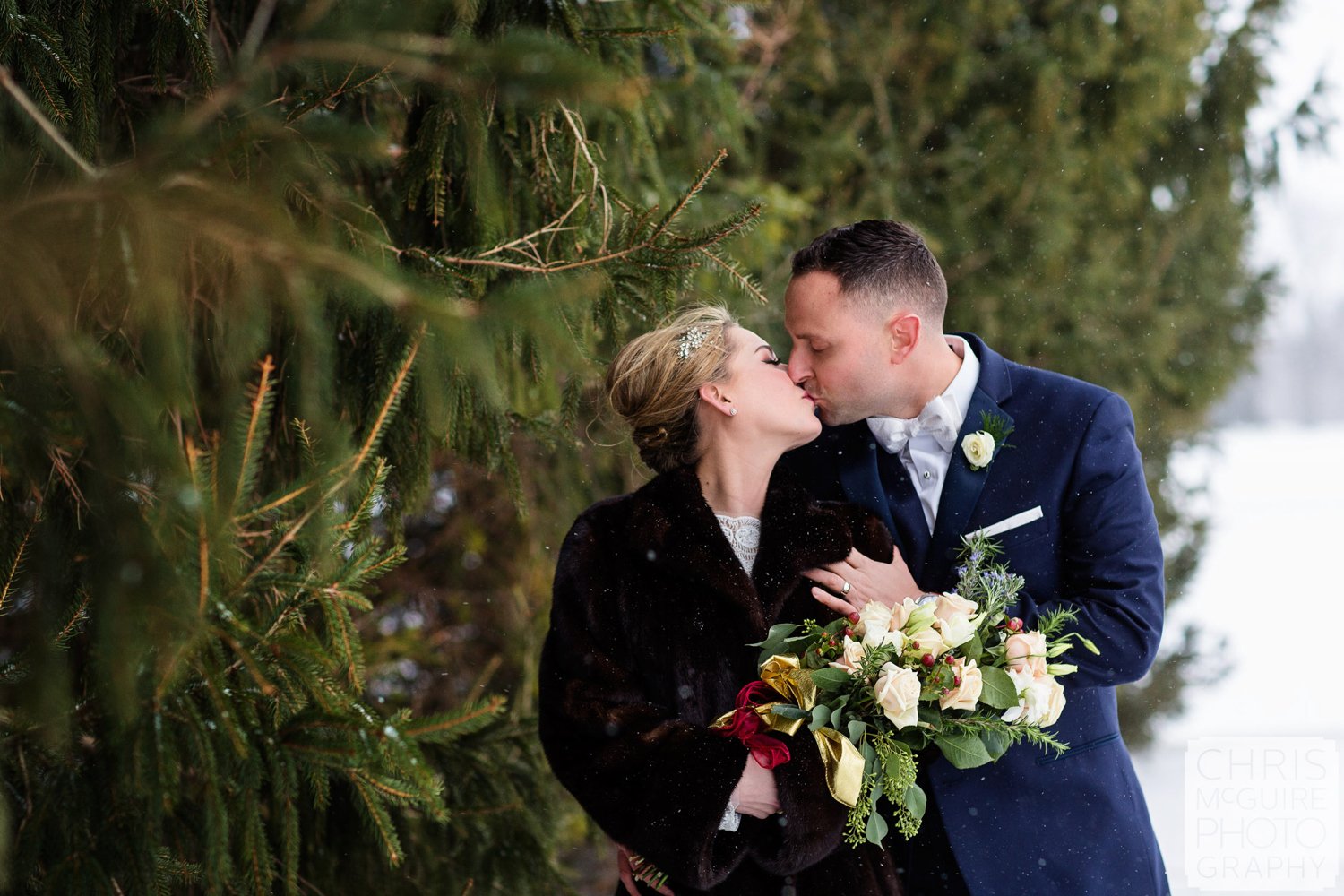 bride groom kissing in snow evergreen trees