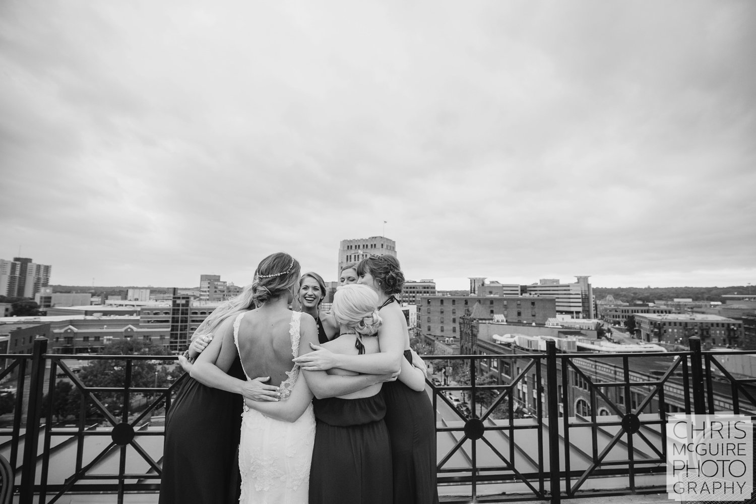 bride and bridesmaids huddle on rooftop