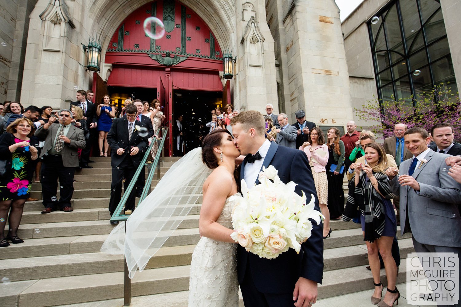 bride groom kiss outside church surrounded by guests peoria