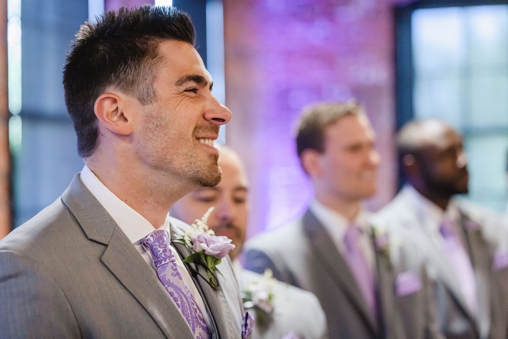 groom smiles as bride walks down aisle