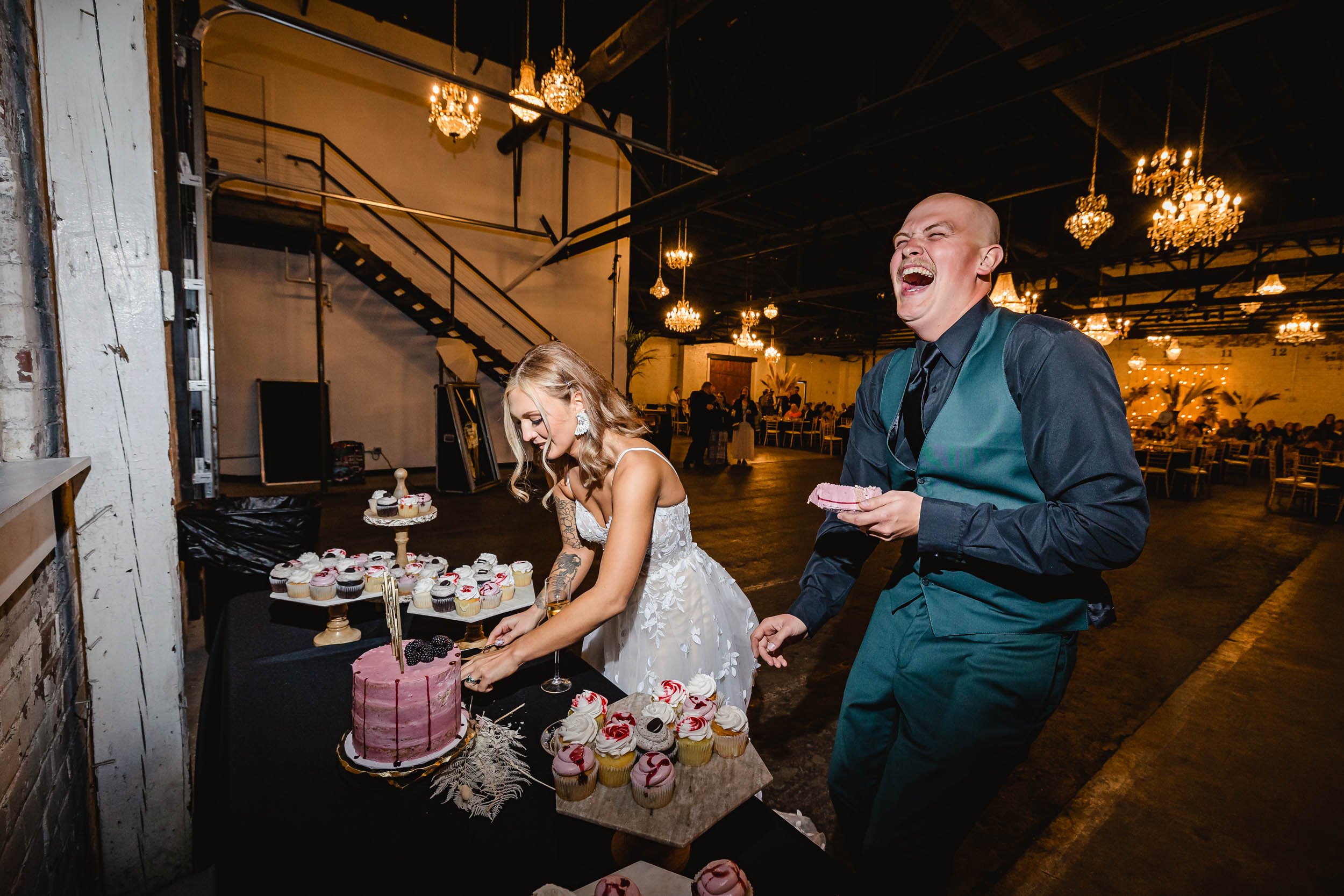 Groom laughing while bride cuts cake