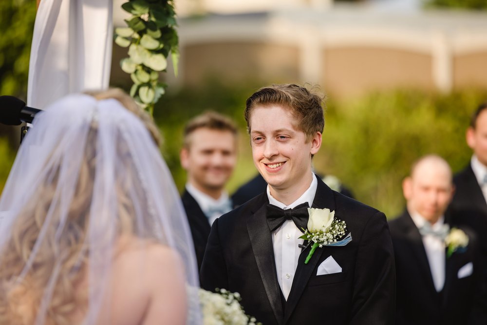 Groom smiles at bride during wedding ceremony
