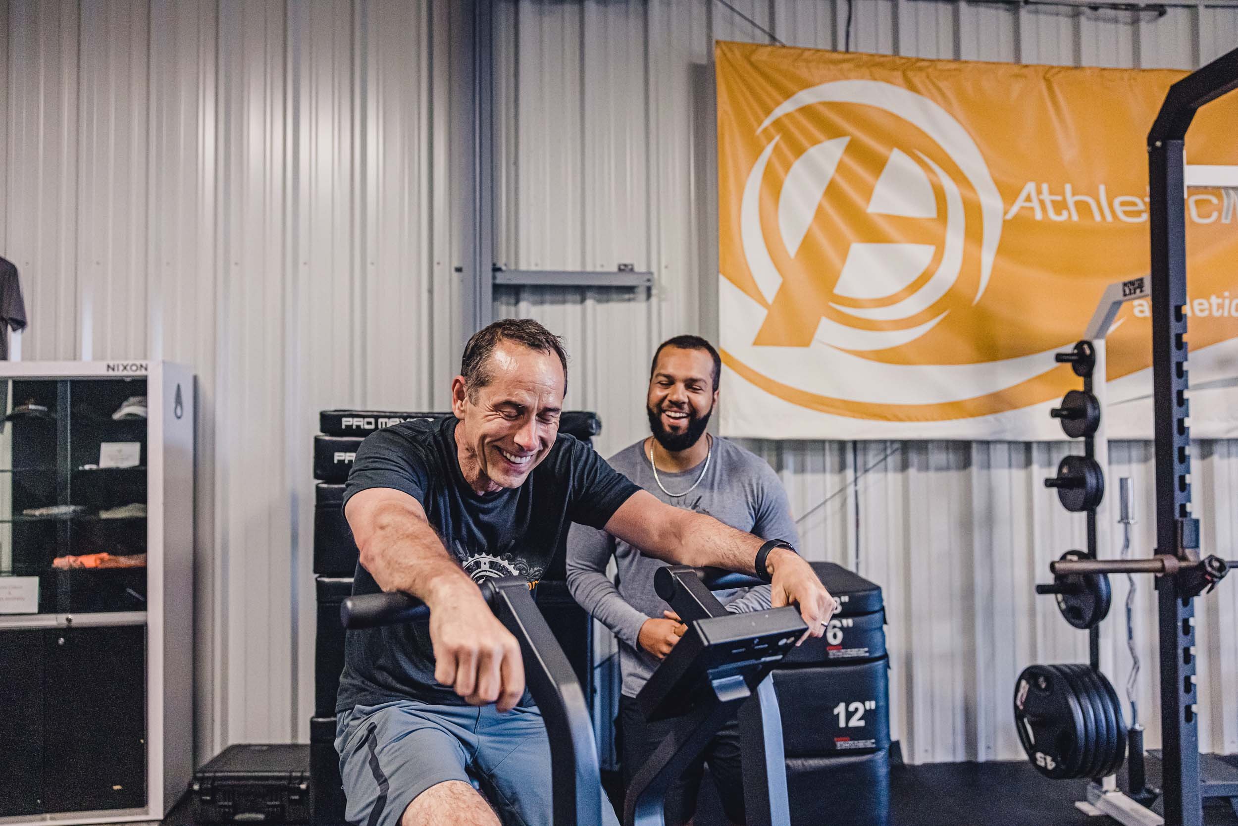 Man laughing on excercise bike with trainer