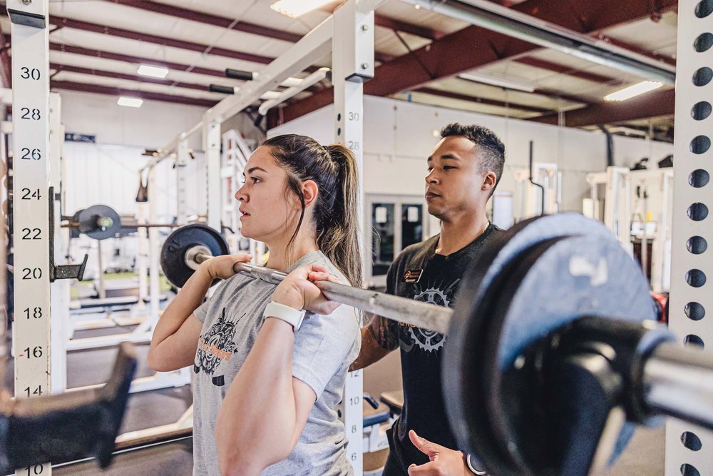 Coach and athlete at gym free weights