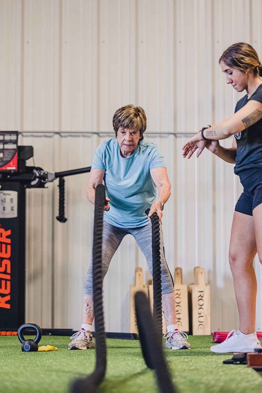 Woman working out with ropes as coach watches