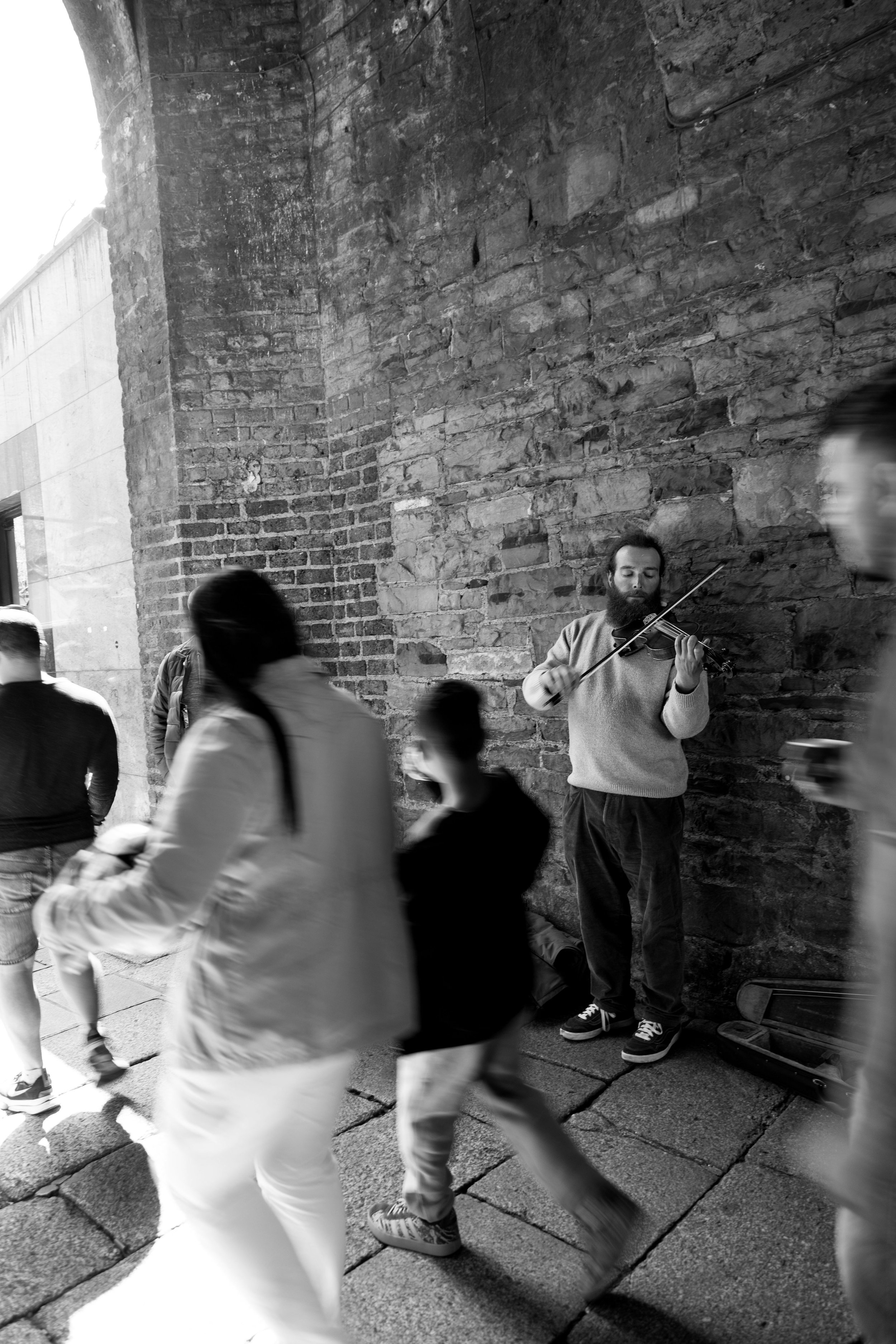 People walk by a man playing the violin in an alley in Dublin, Ireland on May 8, 2025.