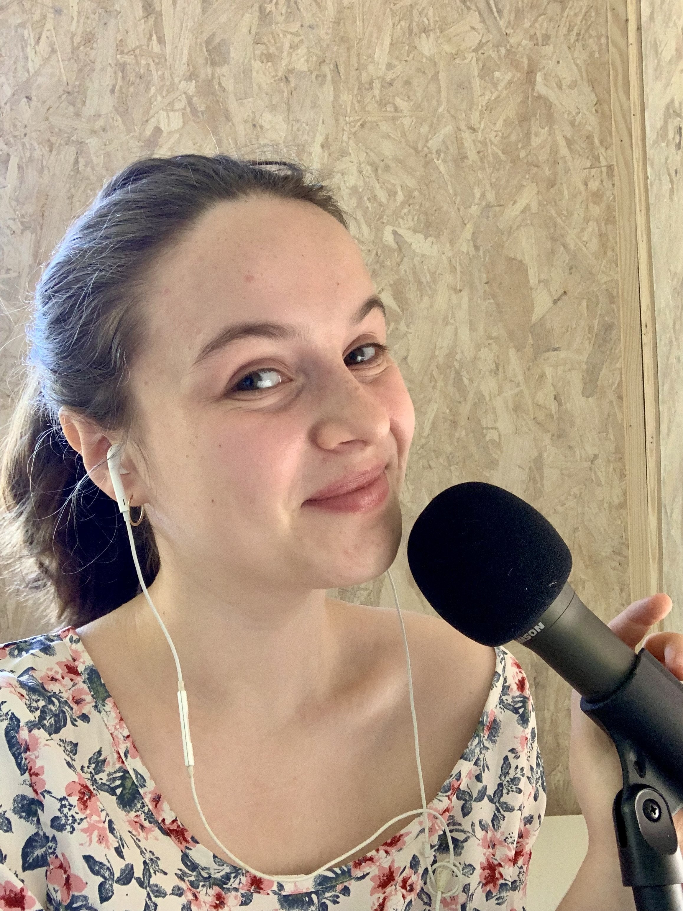 Blossom, a white, brunette woman, using a podcast microphone