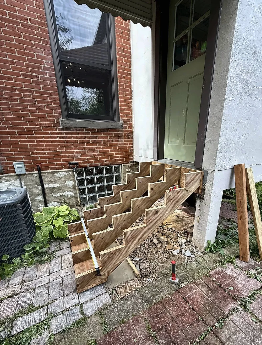 New pressure-treated wood stair stringers set on a gravel base below the back door