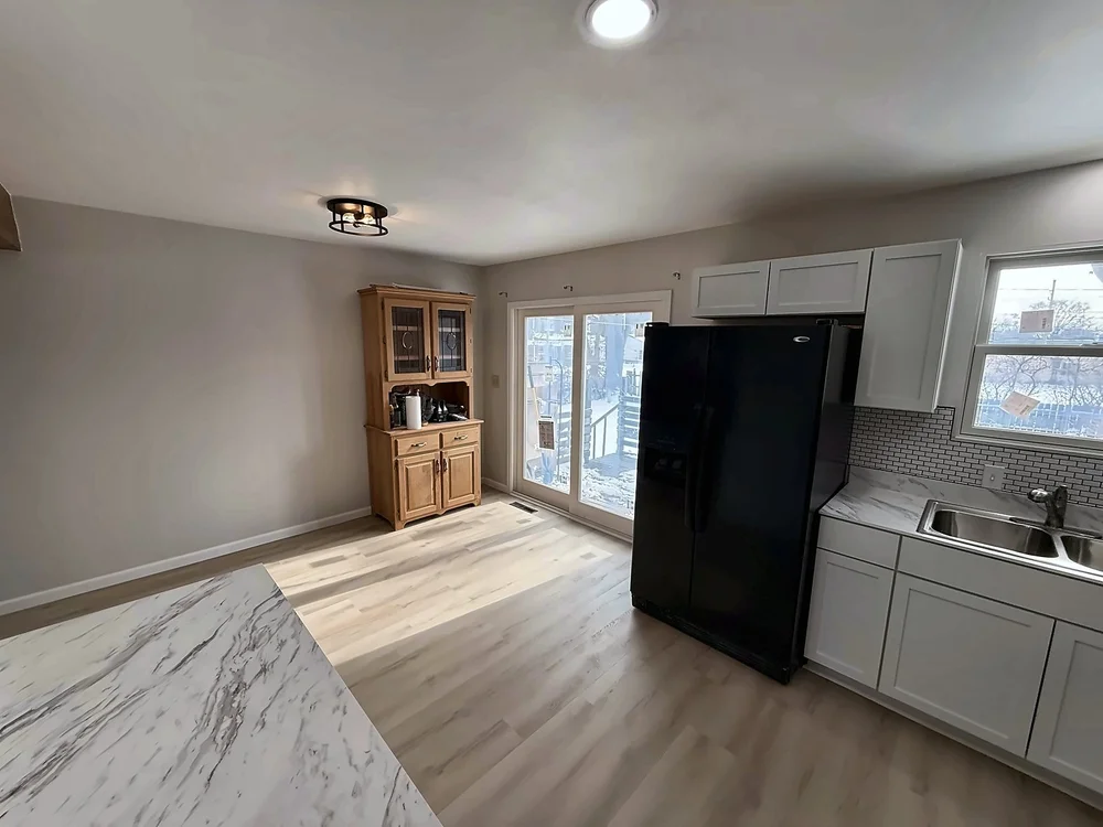 Dining area beside the new kitchen with a new ceiling light, LVP flooring and the marble-look peninsula in the foreground