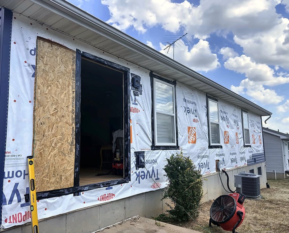 Back wall wrapped in Tyvek housewrap with the old wide door opening partly framed in and sheathed in OSB