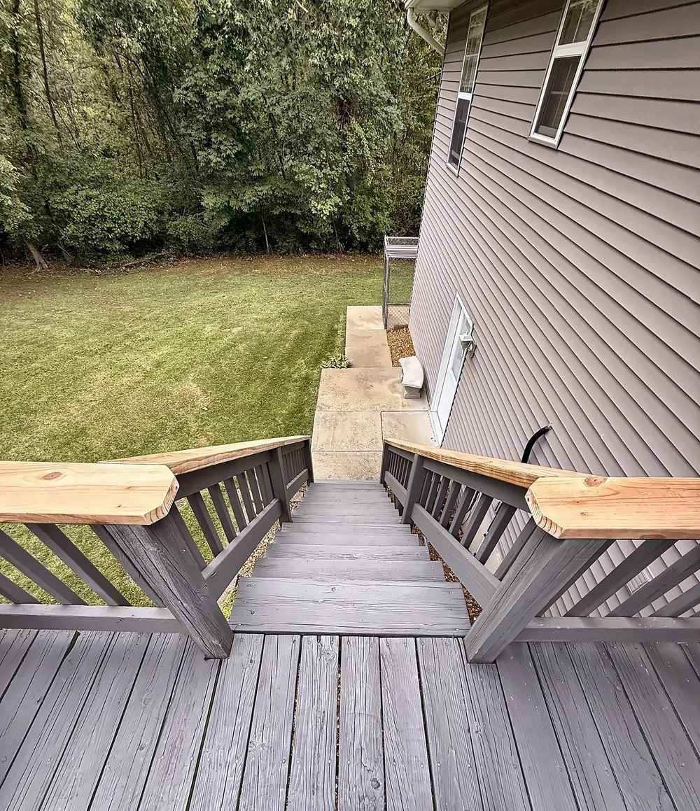 View down the deck stairs with new pressure-treated railing caps cut with clipped corners at the top posts
