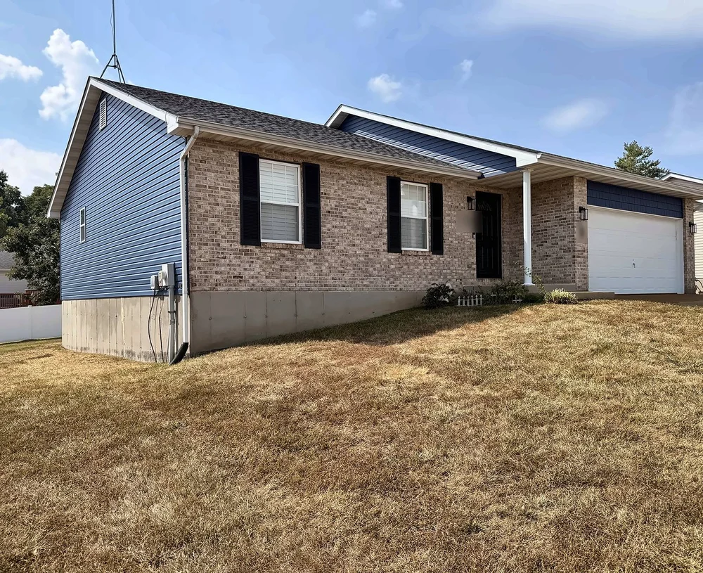 Brick-front ranch home with Midnight Blue vinyl siding on the sides and gables, new black shutters, a black front door behind a new black storm door, and new exterior light fixtures