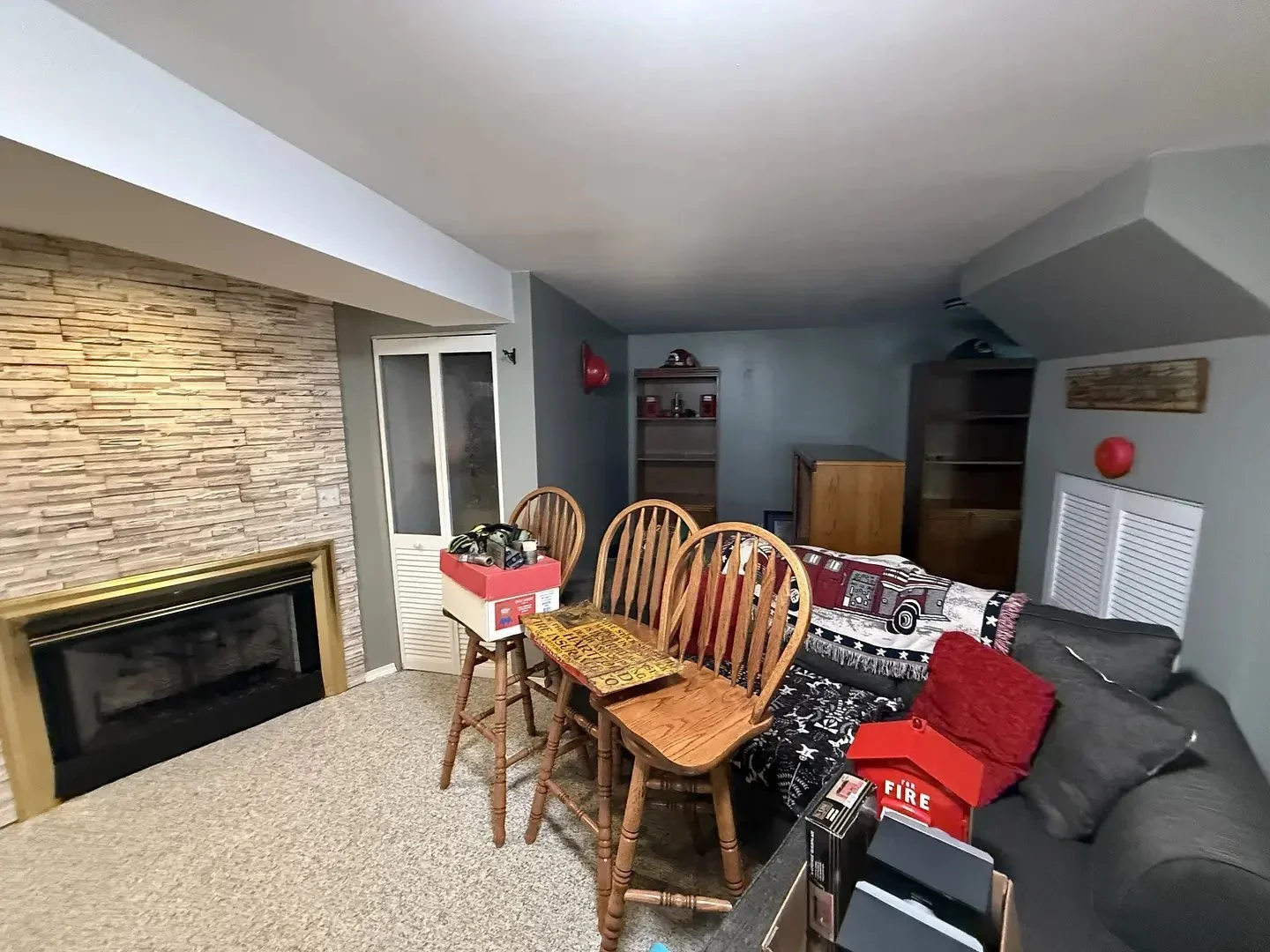 Cozy basement room with fireplace, chairs, and couch