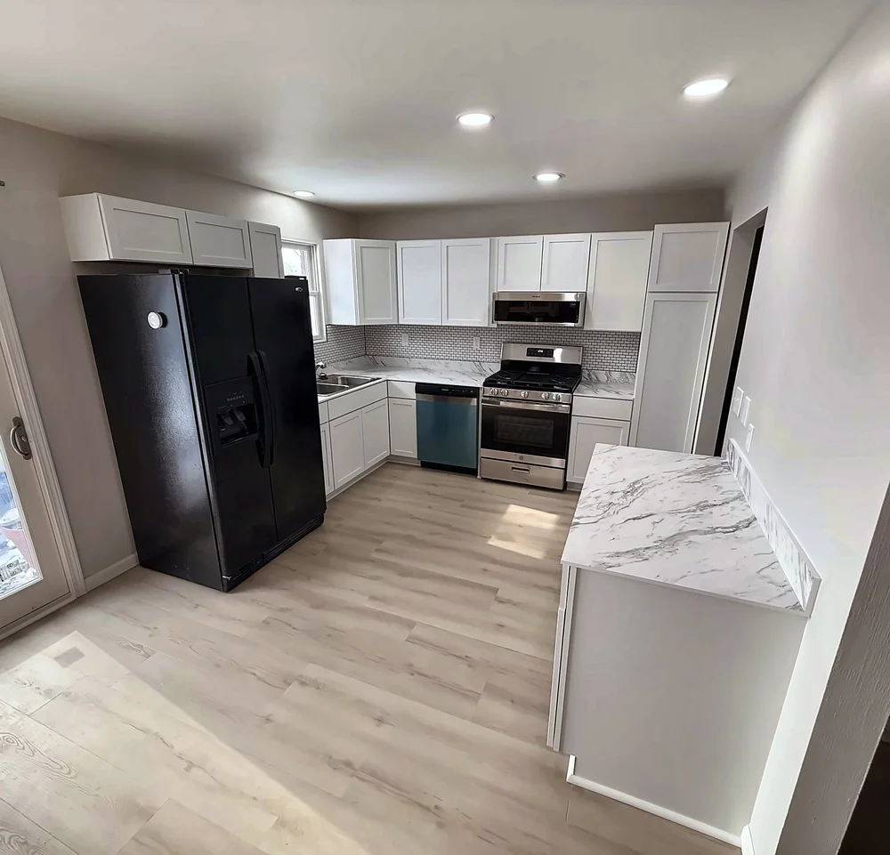 Remodeled kitchen with white shaker cabinets, marble-look counters, a white subway-look backsplash, stainless range and LVP floor