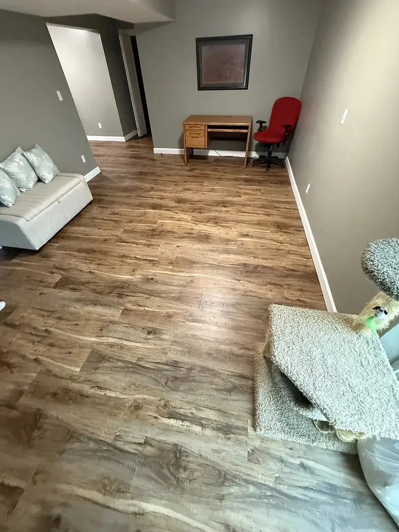 Living room with wood floor, gray walls, a desk, red chair, sofa, and cat tree. Hallway to the left