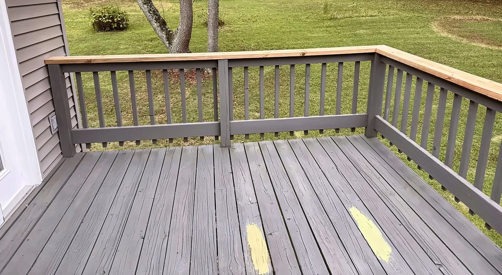 Deck corner with new pressure-treated top caps on gray railing