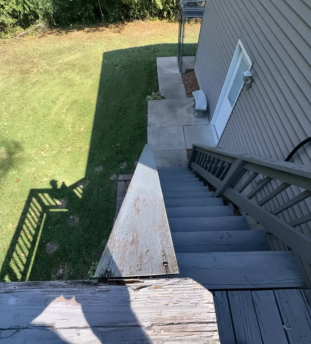 View down the deck stairs from the top with the old peeling gray railing caps