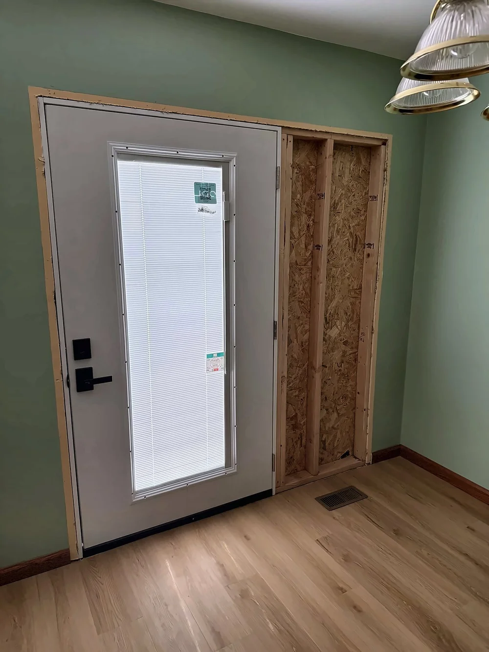 New full-glass door with built-in blinds installed, with the leftover width of the old opening framed in beside it