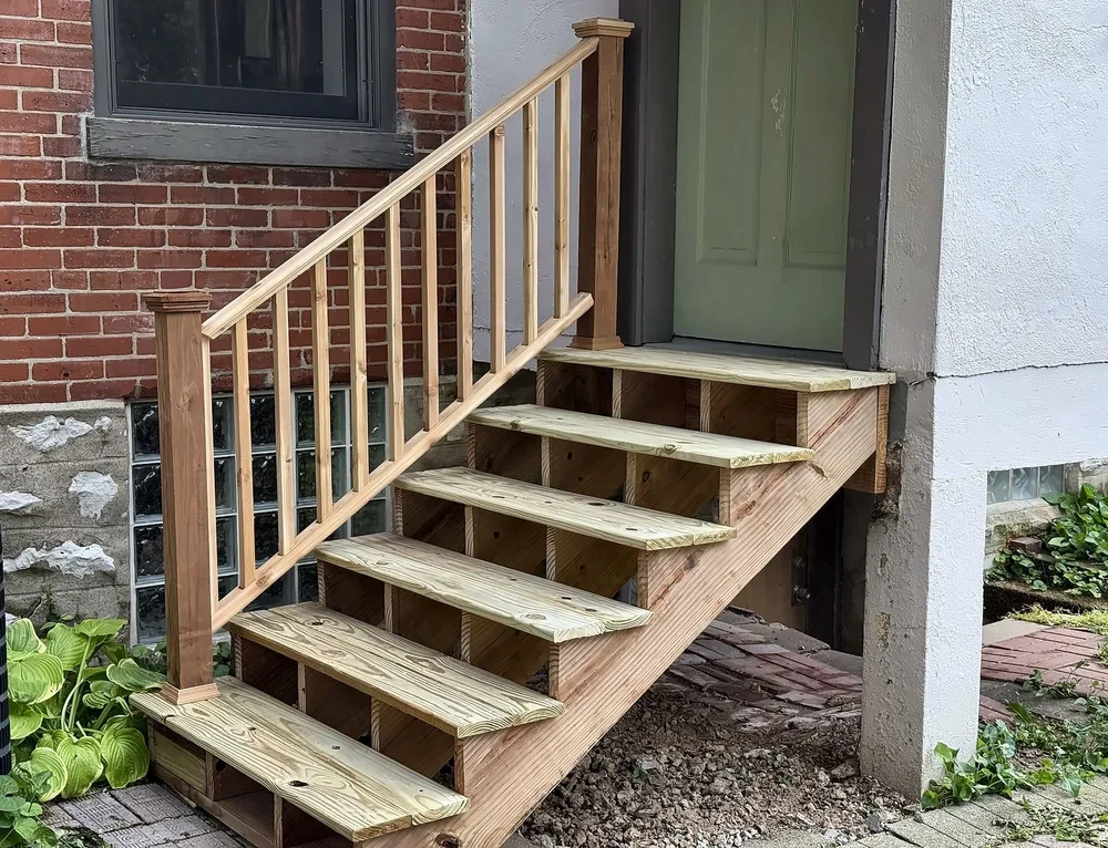 Close-up of new wood back stairs with open risers, square newel posts and 2x2 balusters