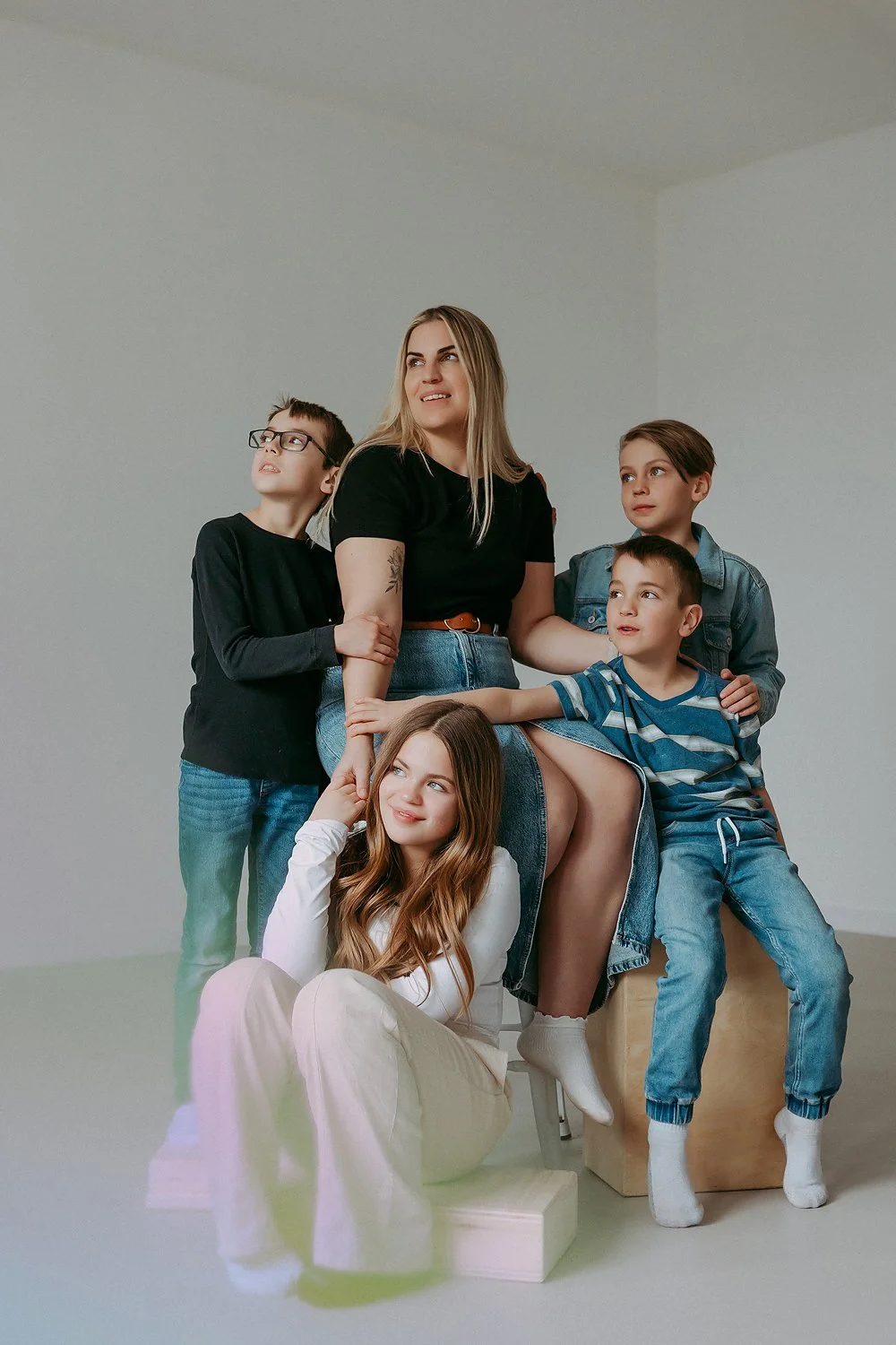 A woman with four children, sitting and standing around her, in a minimalist indoor space.