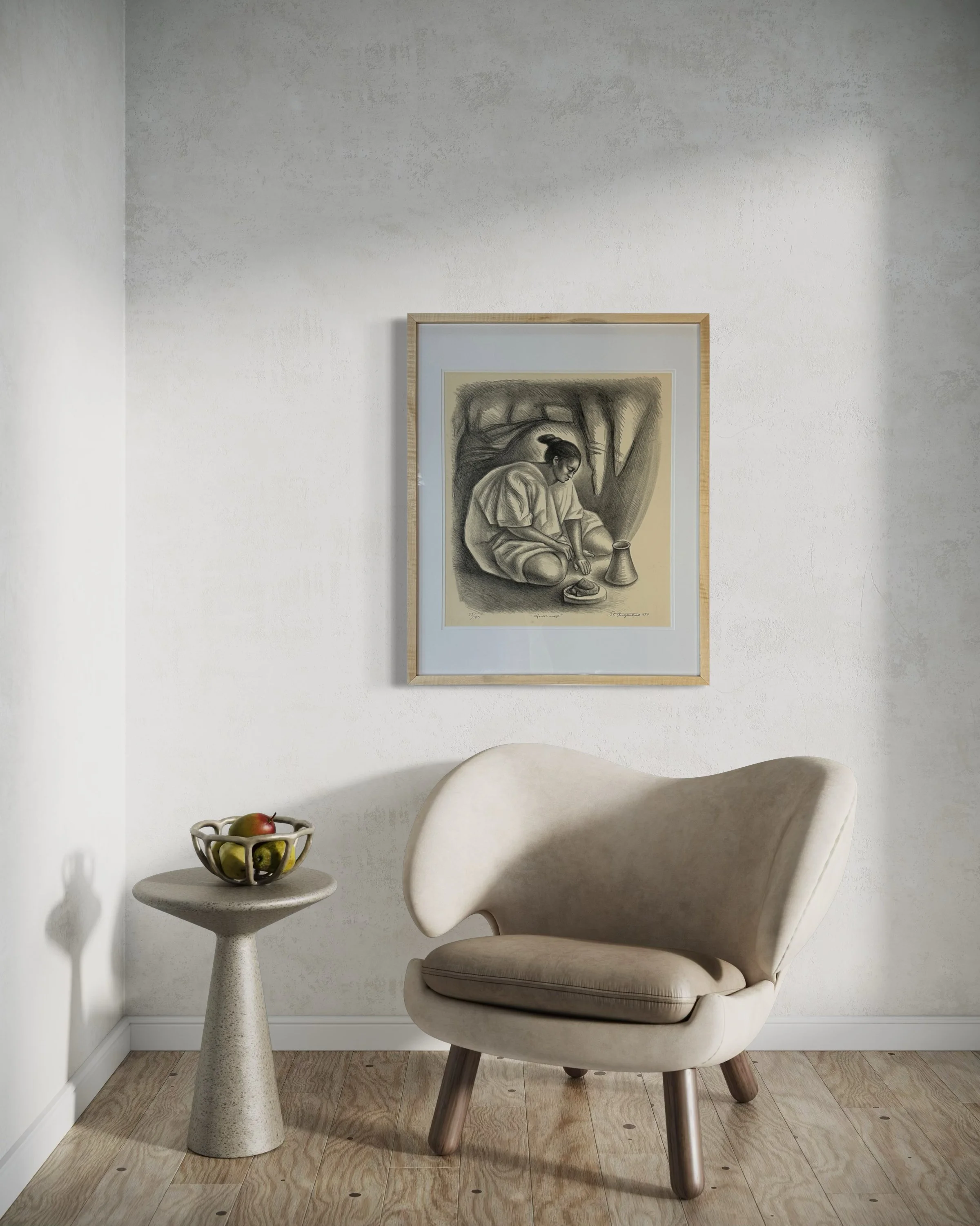 A cozy corner with a white armchair and a small round side table holding a bowl of apples. Curly maple framed artwork depicting a person sitting outdoors is on the white wall behind the chair.