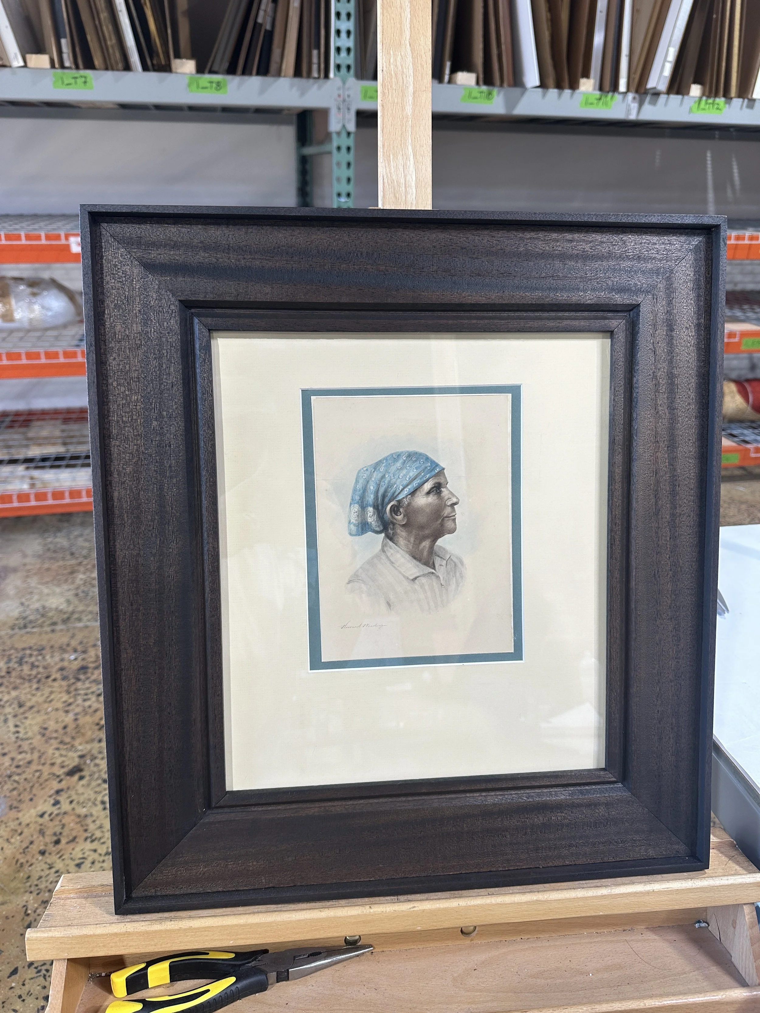 Ebonized step framed artwork of a woman with a blue headscarf and striped shirt, portrait in profile, on a light background.
