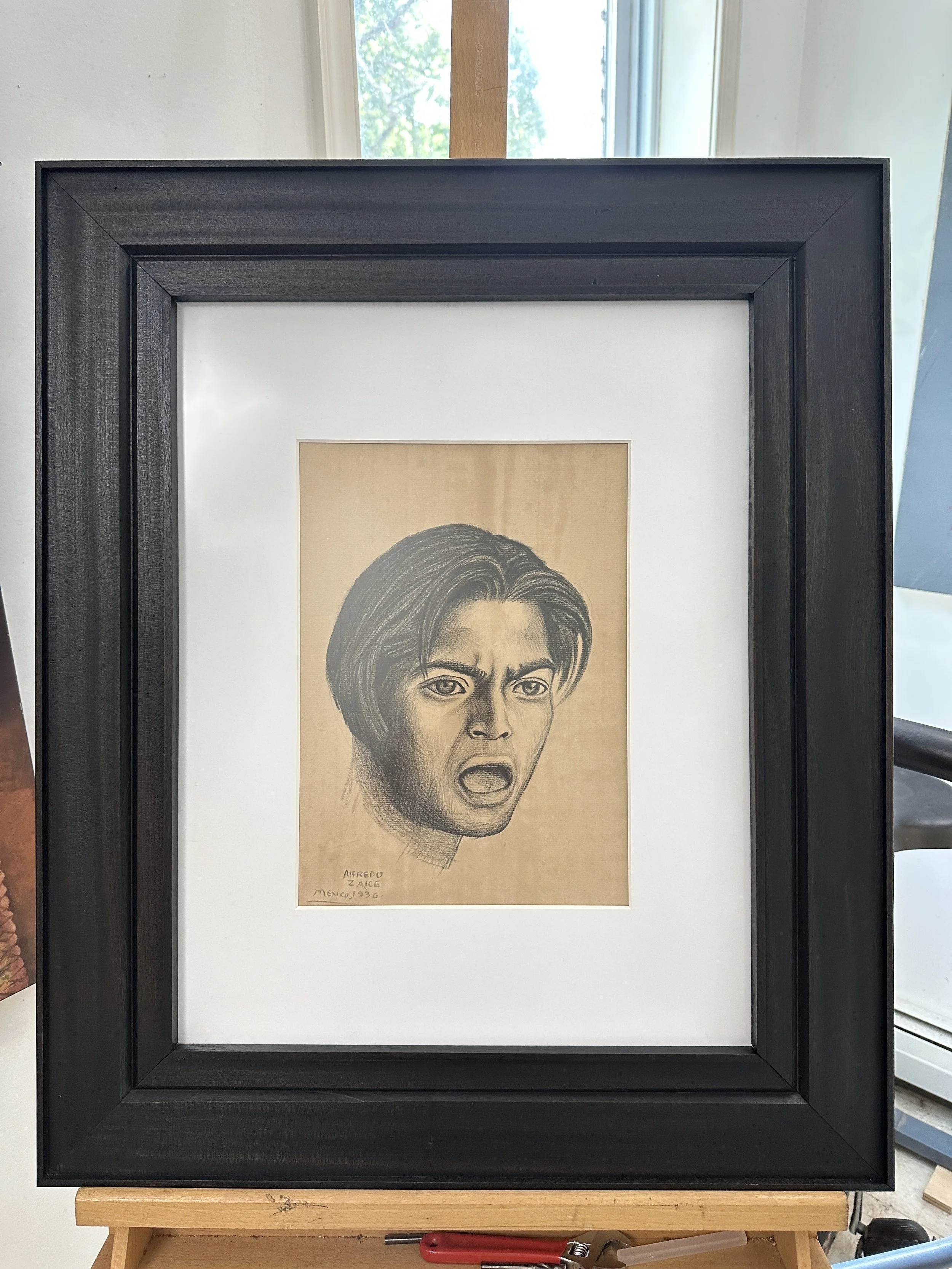 A framed sketch of a woman with short hair and an angry or determined expression, signed with the name Alfredu and dated Mexico 1936.