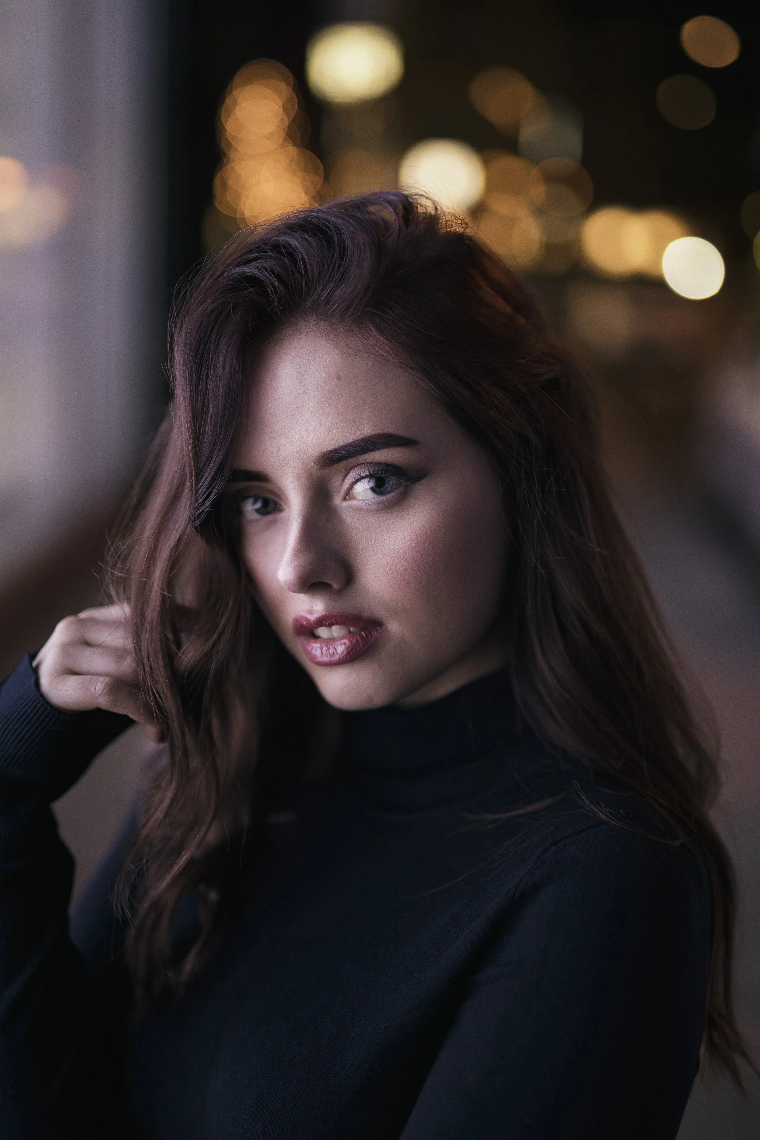 Portrait einer rothaarige Frau mit Rollkragenpulli in einer Stadt, beleuchtet durch ein Leuchtschild