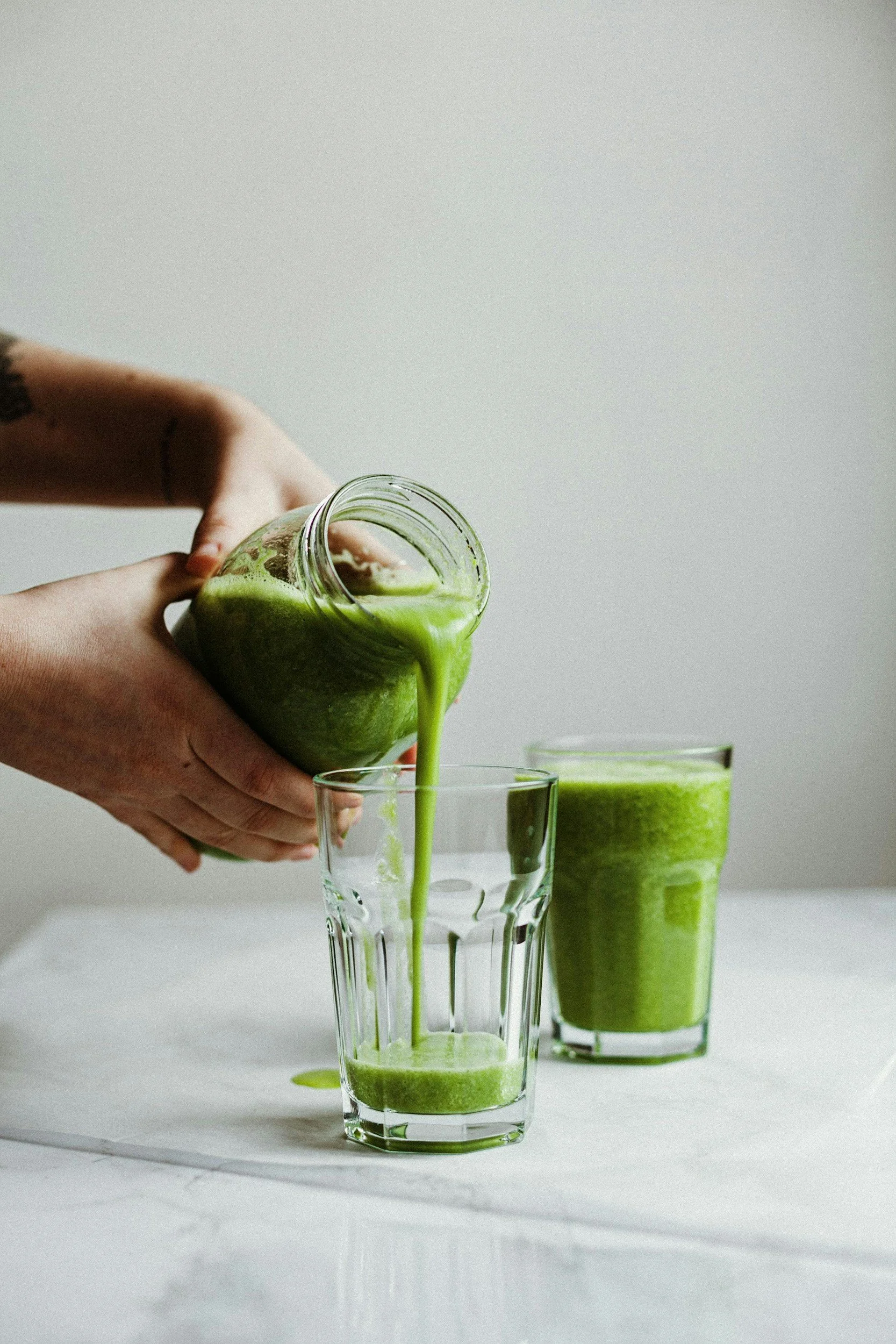 Green smoothie being poured into glass | Prioritizing your health | Scarlet Oak Wellness