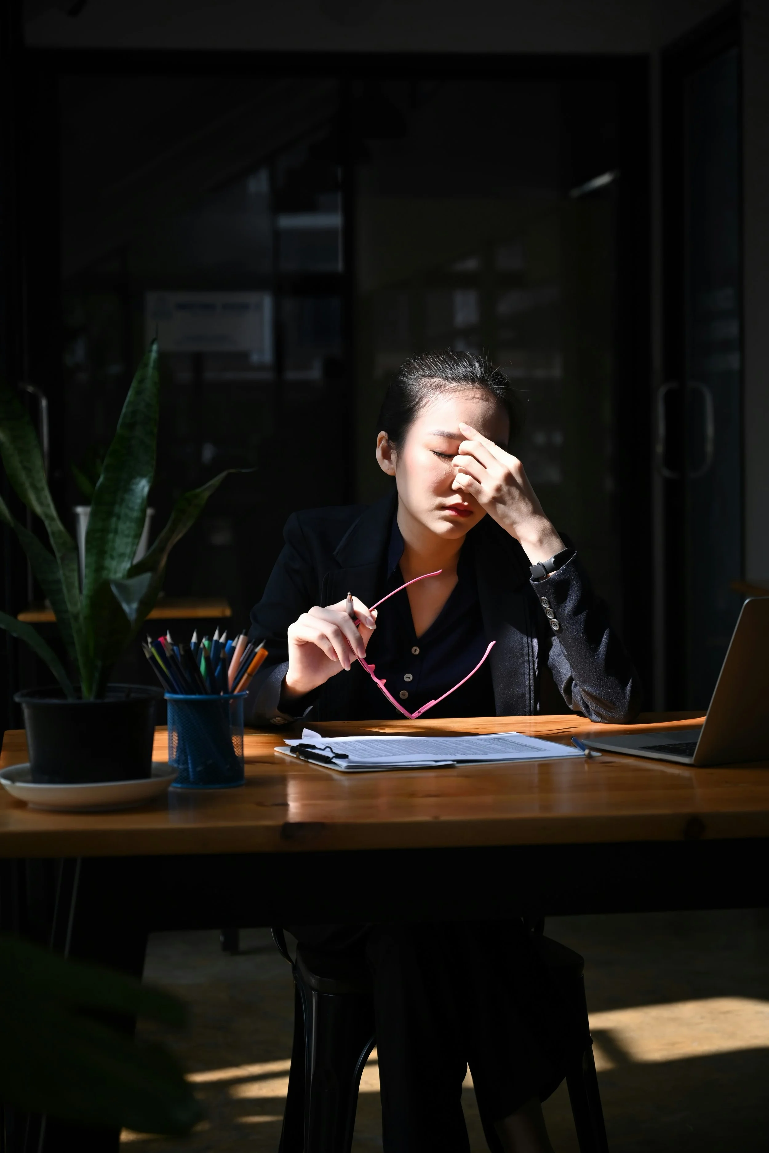 Women working on forms, glasses removed, looking exhausted and stressed | Hormones are a driver in Perimenopause | Scarlet Oak Wellness