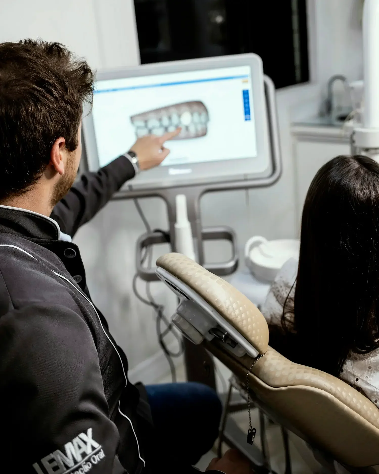 A dentist showing a digital x-ray of a patient's teeth on a computer screen.
