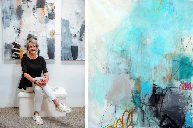 artist Julie Schumer sitting infront of her abstract blue and grey large paintings on studio wall