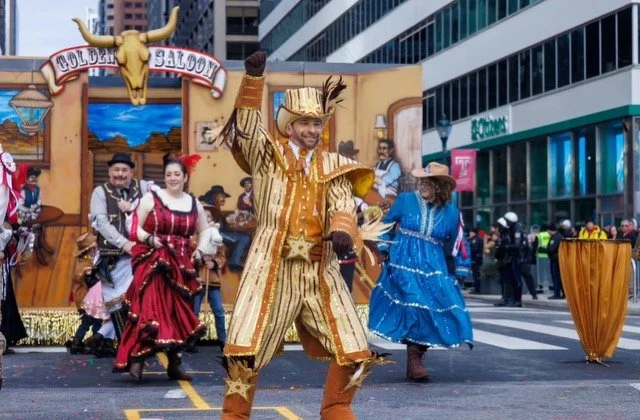 People dressed in cowboy and western costumes performing in a parade on a city street.