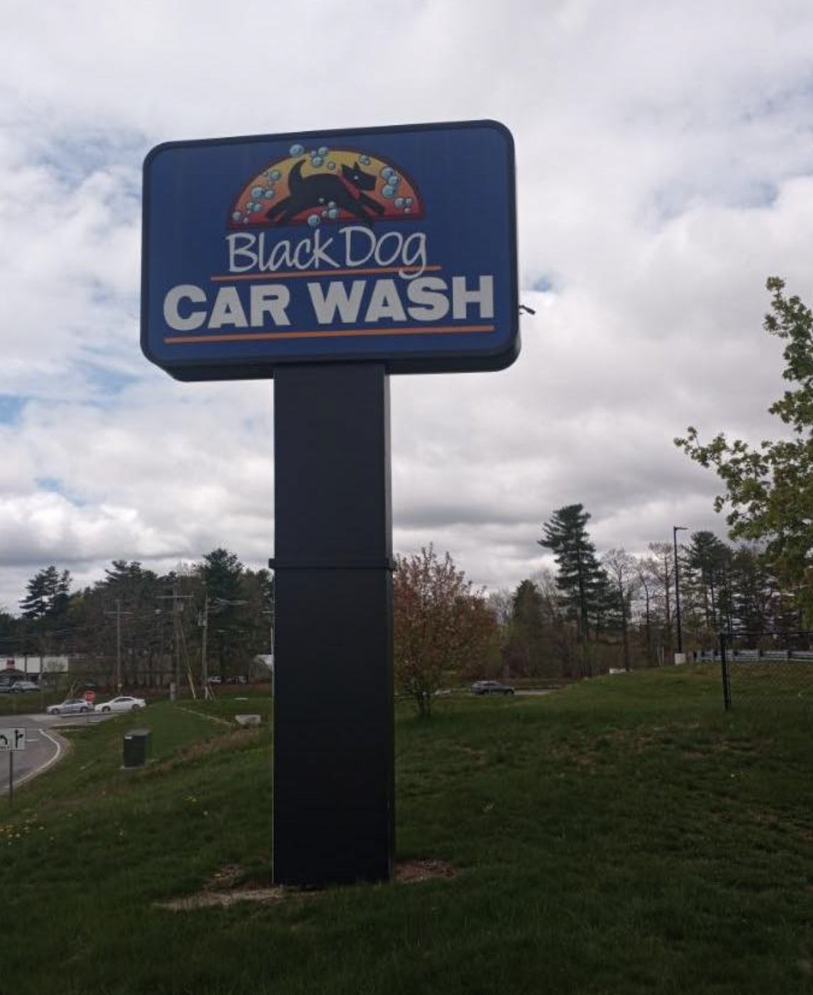 Sign for Black Dog Car Wash with a cartoon dog logo, blue background, and white text