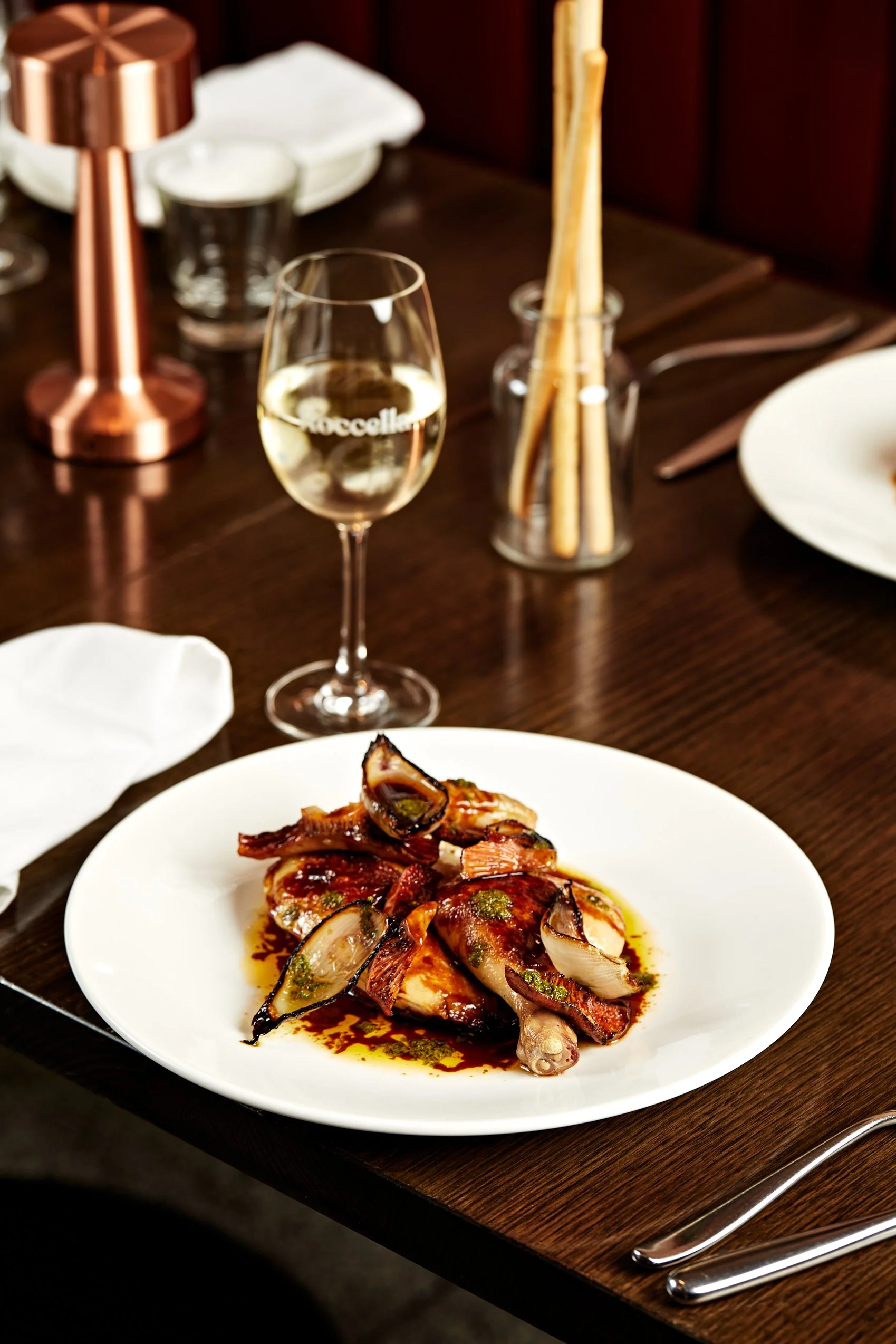 An image of a roast chicken and glass of italian wine on a table from the Roccella functions set menu.