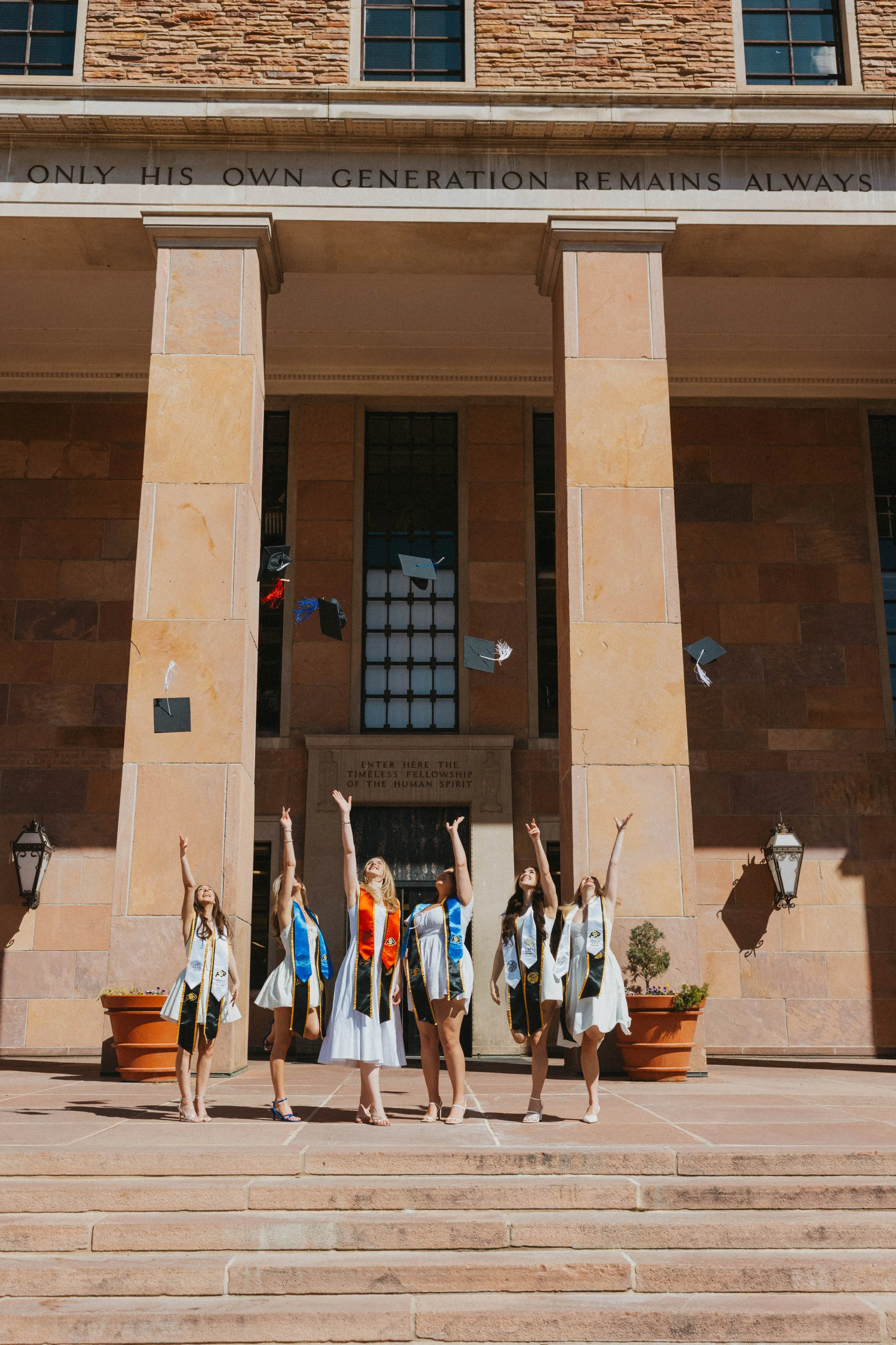 Grads tossing caps together at Norlin Library