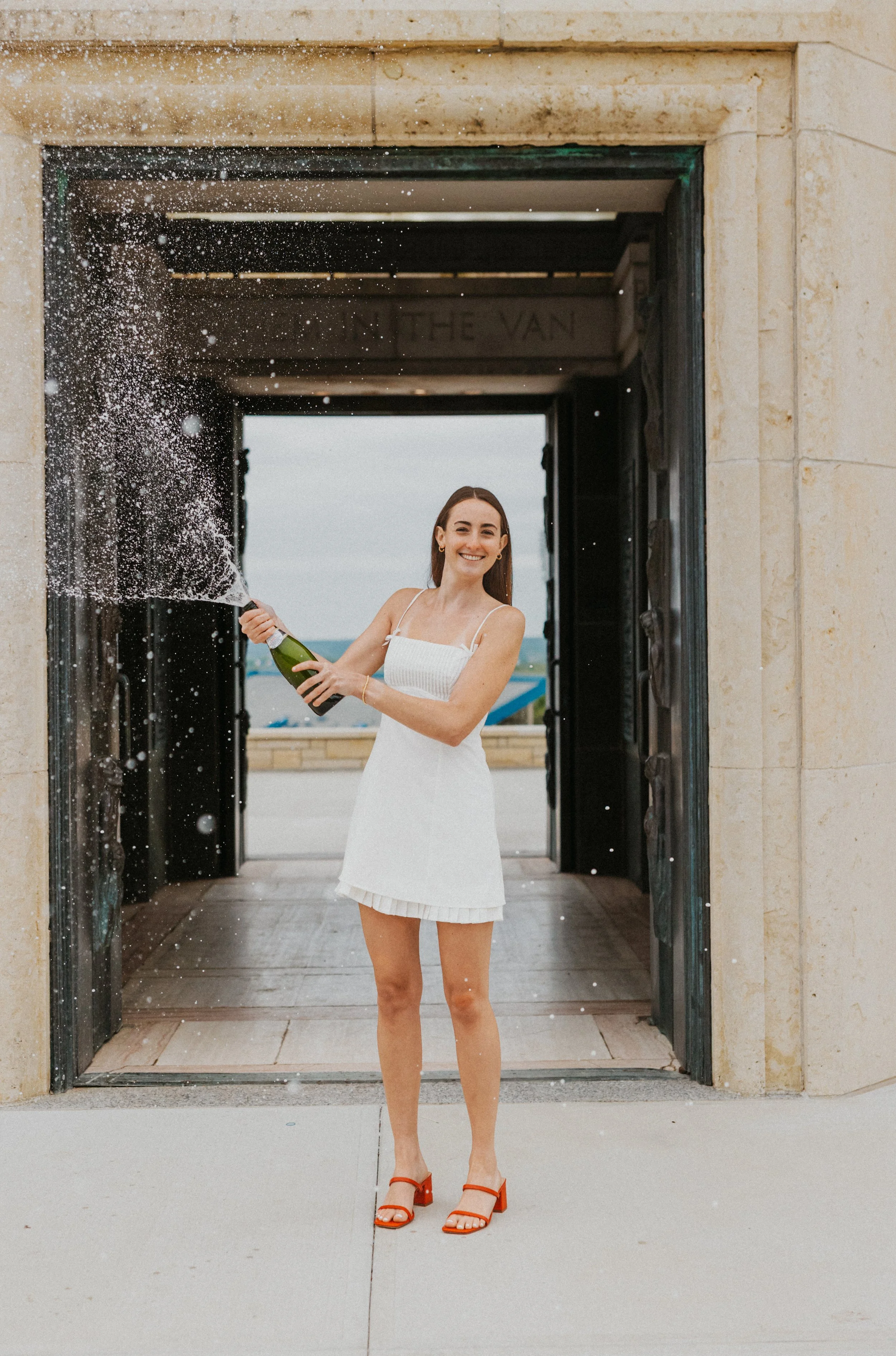 Graduate popping champagne on KU Campus