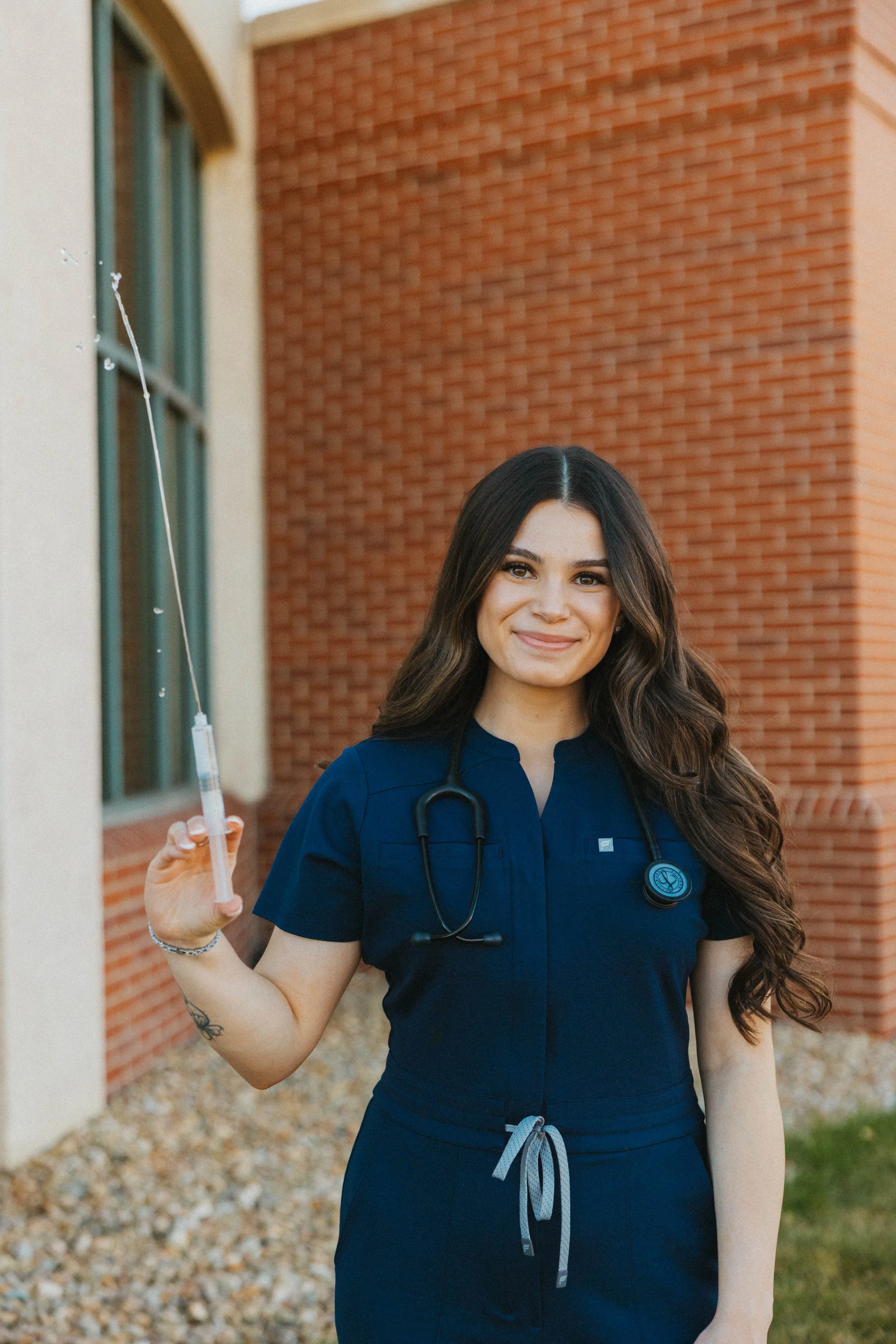 Nursing grad student holding out a syringe while smiling