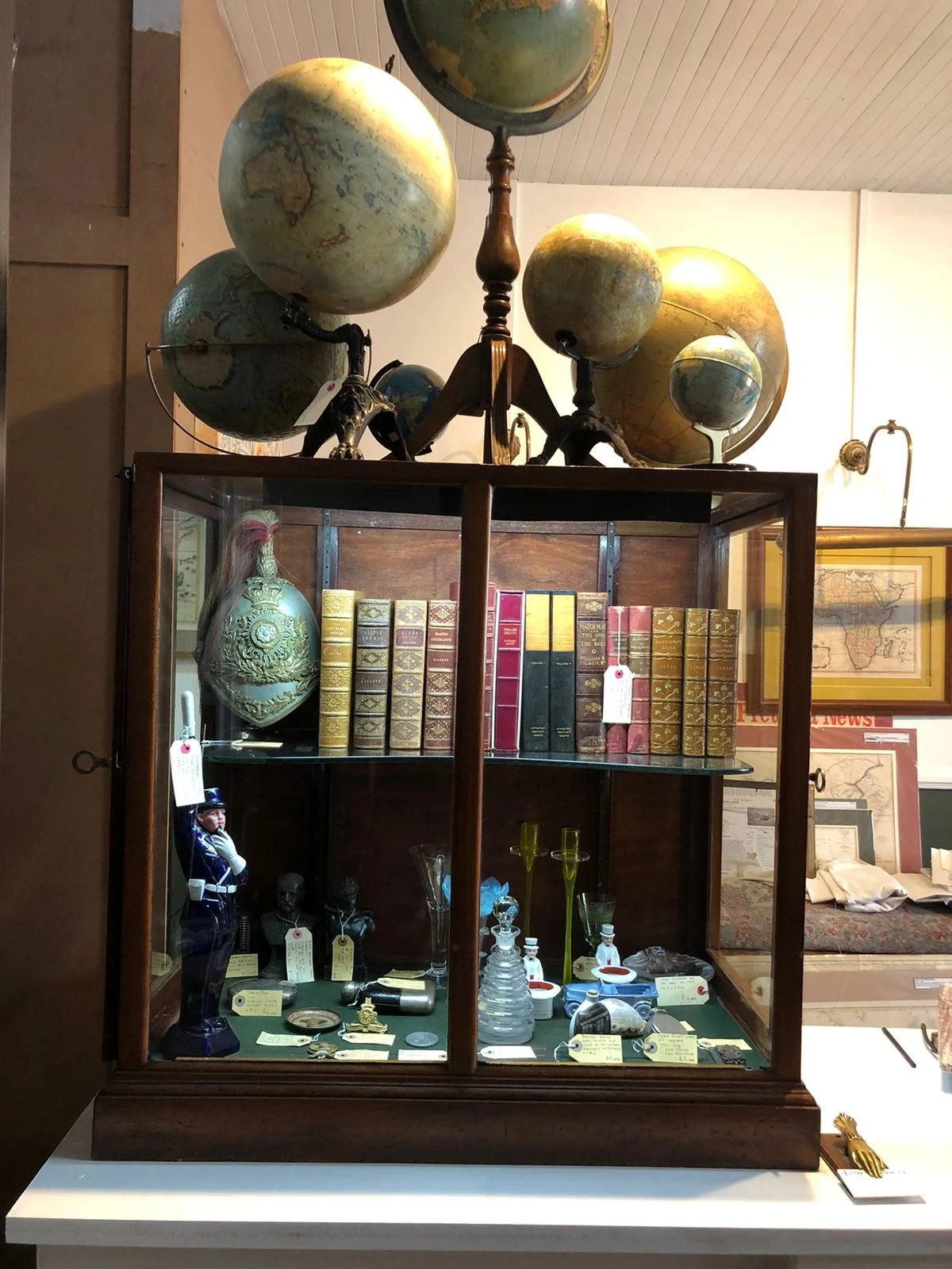 A display case with books and antique items, topped with globes and decorative objects.