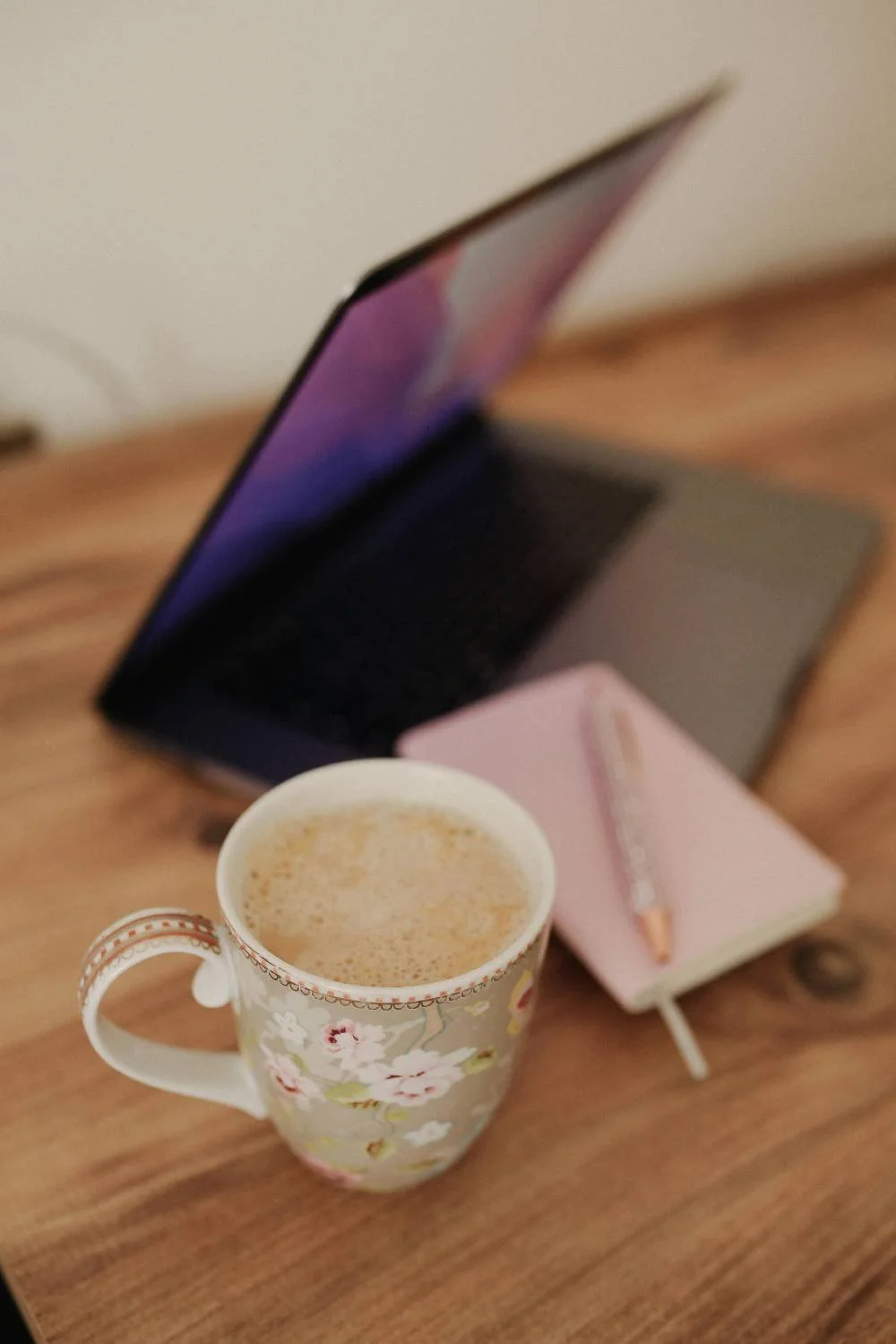 Laptop mit Website, Tasse und Notizbuch