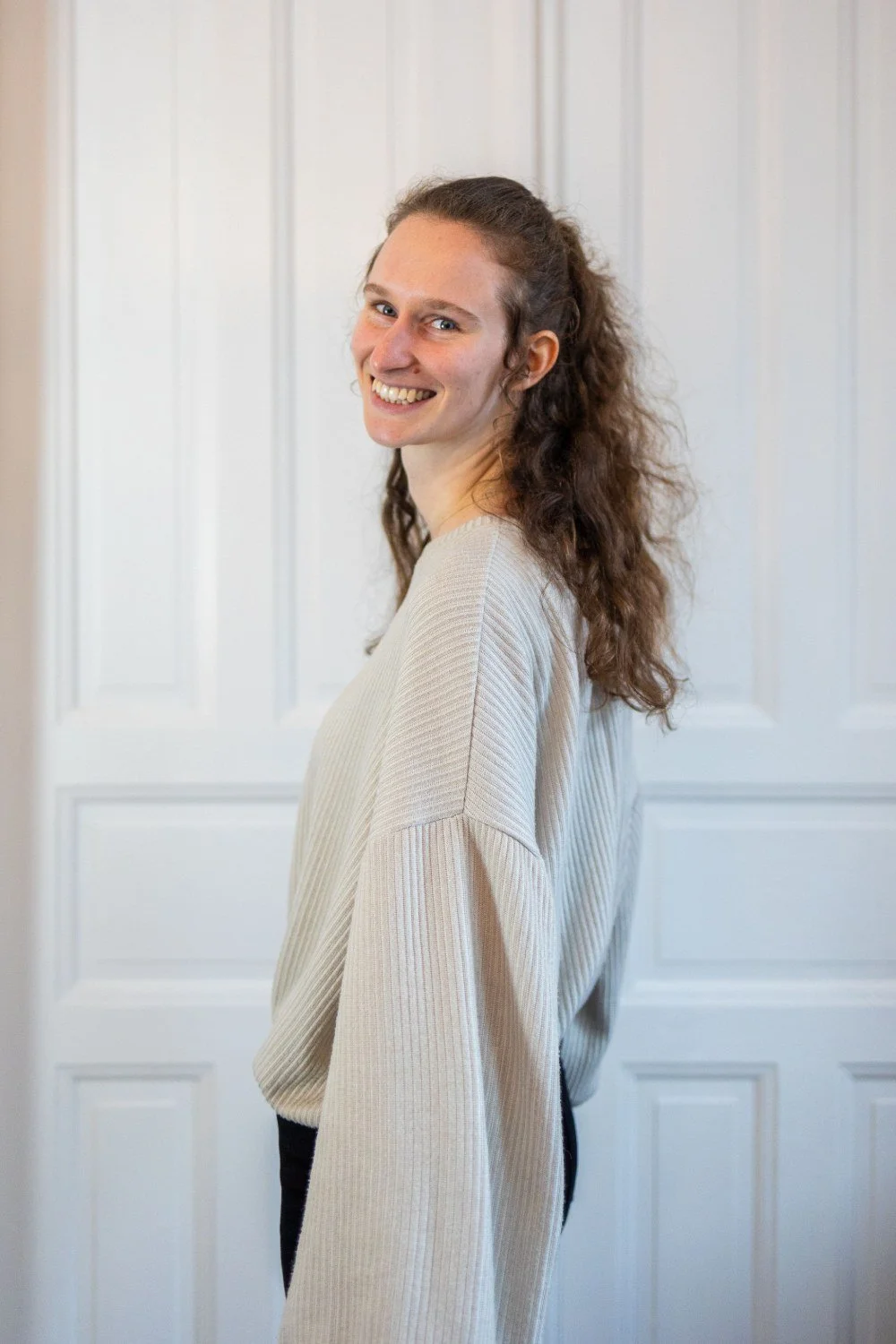 Webdesignerin Maike schaut über Schulter in Kamera