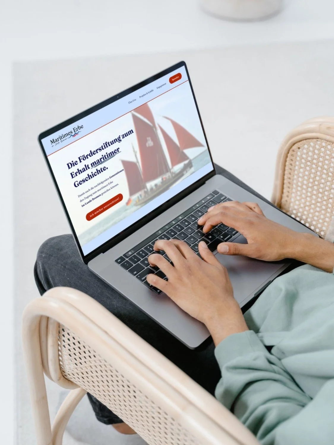 Laptop mit Stiftungs Website auf Schoß einer Person