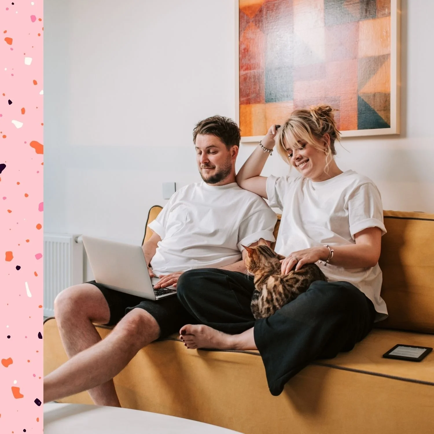 Paar sitzt mit Katze und Laptop auf gelbem Sofa und spricht über Website Relaunch